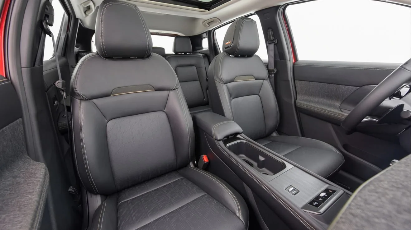 Detalhe dos bancos dianteiros do novo Nissan Kicks 2025 com acabamento premium em couro preto, costuras contrastantes e tecnologia Zero Gravity, acompanhados do console central com apoio de braço e comandos do e-Shifter; imagem também destaca o espaço interno ampliado e o teto solar panorâmico, reforçando o conforto e sofisticação do SUV compacto brasileiro.