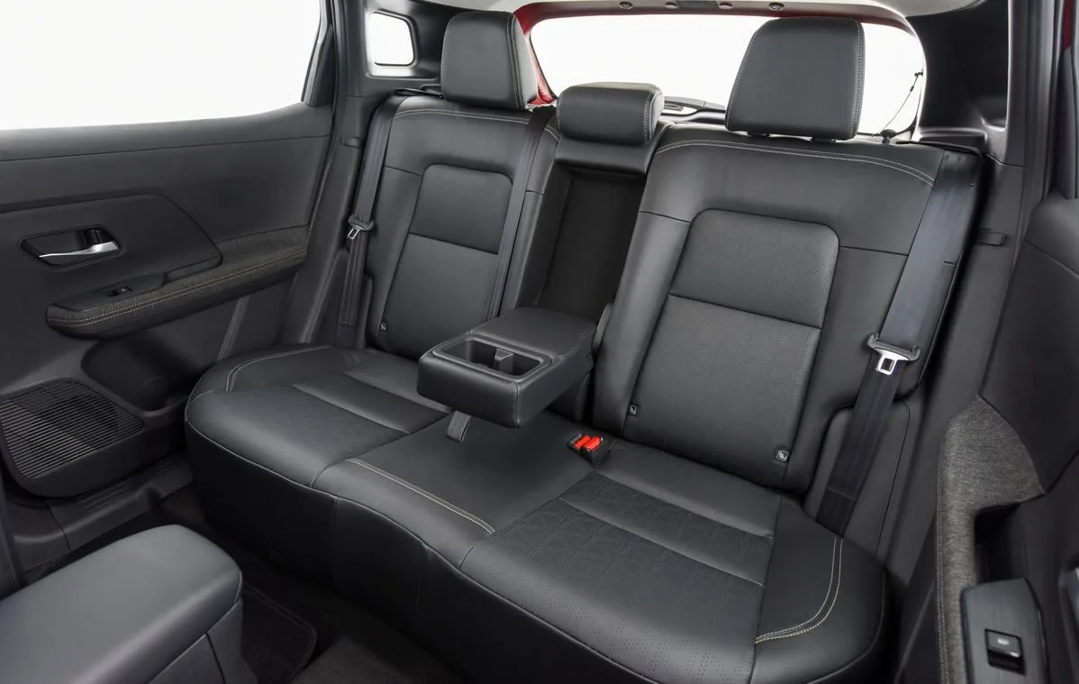Assentos traseiros do novo Nissan Kicks 2025 com acabamento premium em couro preto, costuras aparentes e apoio de braço central retrátil com porta-copos, destacando a tecnologia Zero Gravity, cintos de três pontos em todas as posições e fixações Isofix para cadeirinhas, evidenciando o conforto e a segurança dos passageiros no SUV compacto nacional.