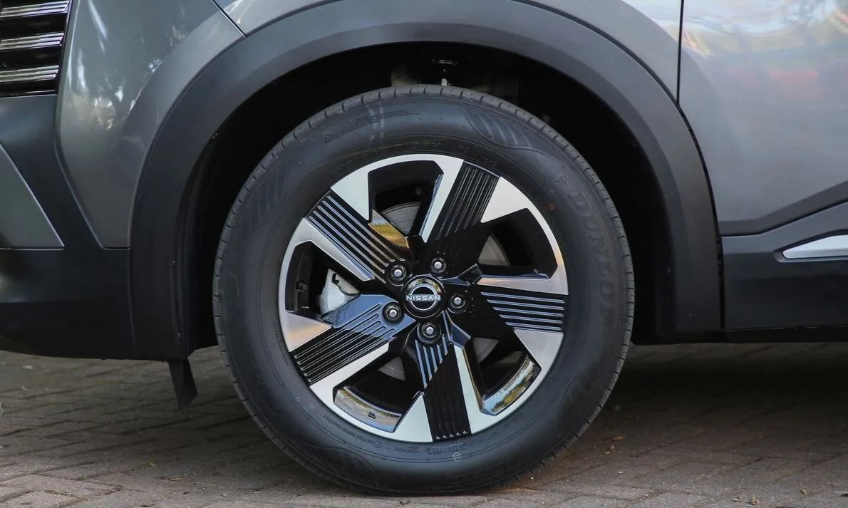Detalhe da roda de liga leve aro 19 do novo Nissan Kicks 2025 com acabamento diamantado e pintura em preto brilhante, equipada com pneus Dunlop, evidenciando o design exclusivo, esportivo e robusto do SUV compacto produzido no Brasil.