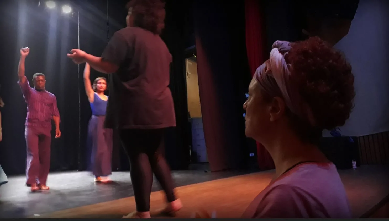 A diretora Luísa Machala observa atentamente o ensaio geral do espetáculo “Vazante”, enquanto orienta os formandos no palco do Teatro Marília, em Belo Horizonte.