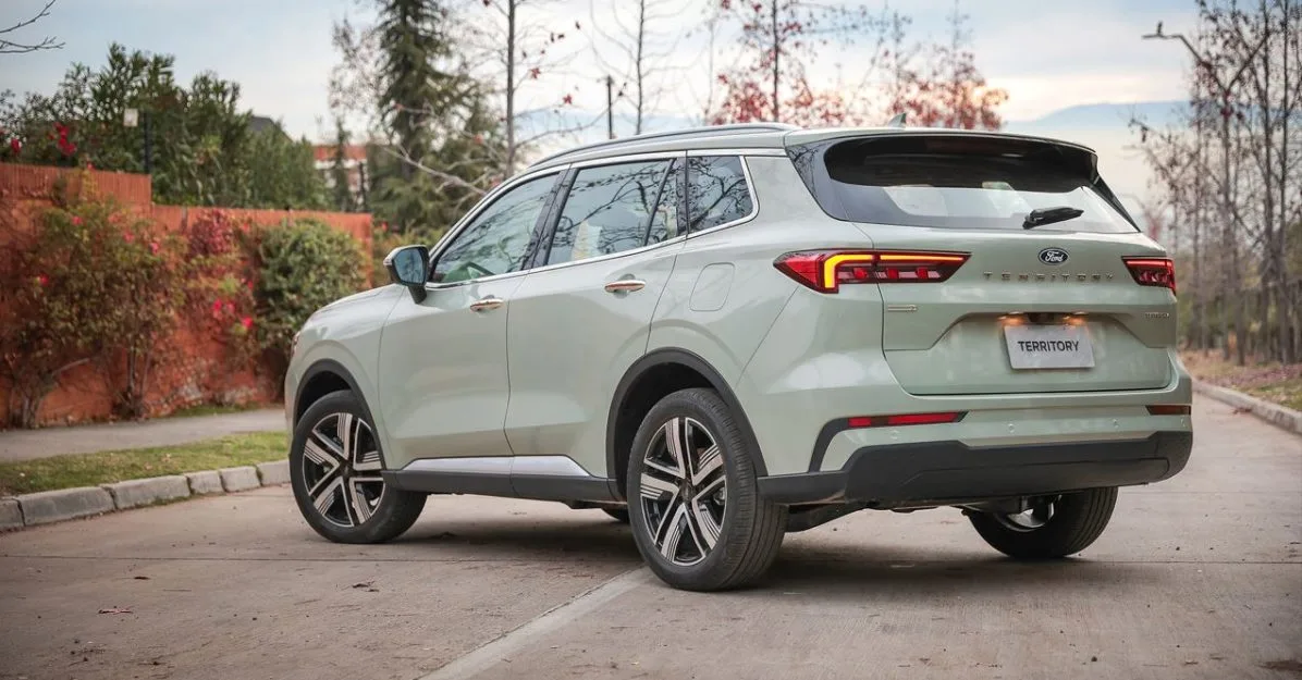 Traseira do Novo Ford Territory 2026 Titanium na cor Verde Oásis, em destaque com lanternas em LED interligadas, assinatura visual moderna e para-choque redesenhado, estacionado em via arborizada sob luz suave do entardecer.