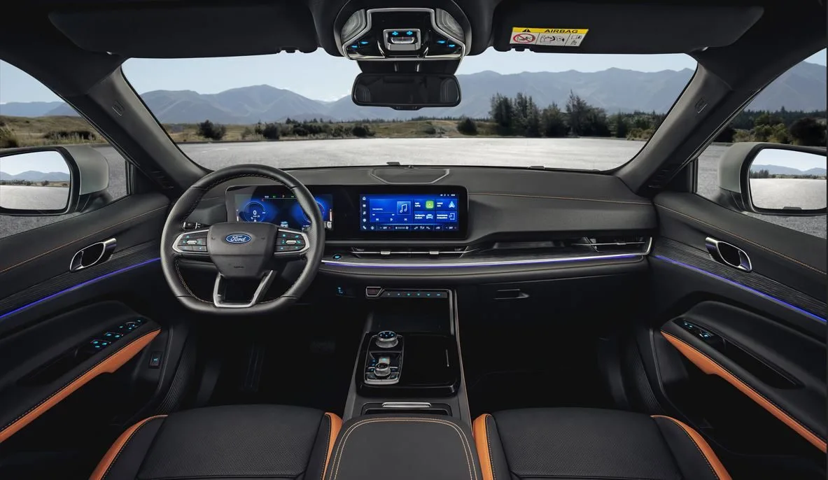 Interior do Novo Ford Territory 2026 Titanium com acabamento premium em Preto Dominó e detalhes em Marrom Manuka, destacando painel digital de 12,3", central multimídia integrada, iluminação ambiente em LED e volante multifuncional com comandos intuitivos.