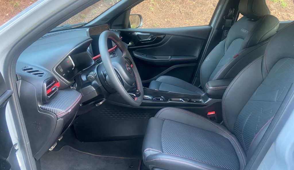Interior dianteiro do Fastback Abarth 2025 com bancos esportivos em couro ecológico, costuras vermelhas e acabamento premium.