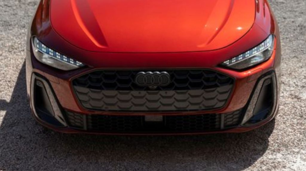 Detalhe frontal do novo Audi A5 2025 na cor vermelha, com grade hexagonal imponente e faróis full-LED com assinatura visual distinta.