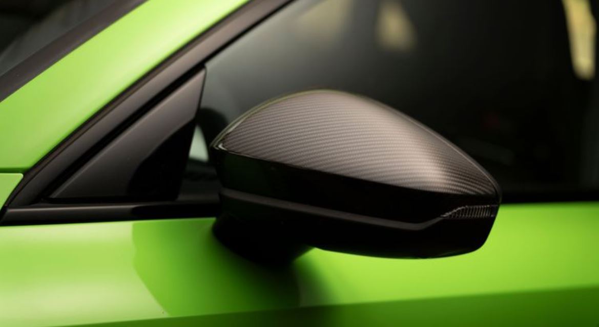 Close do retrovisor externo do Audi RS 3 Sedan Track, com capa em fibra de carbono sobre pintura Verde Kyalami, evidenciando acabamento esportivo.