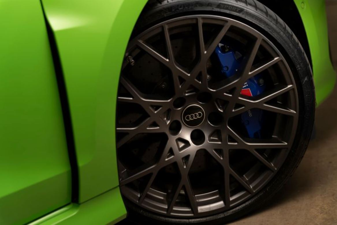 Detalhe da roda de liga leve do Audi RS 3 Sedan Track com acabamento escurecido e pinça de freio cerâmica na cor azul com logotipo RS.