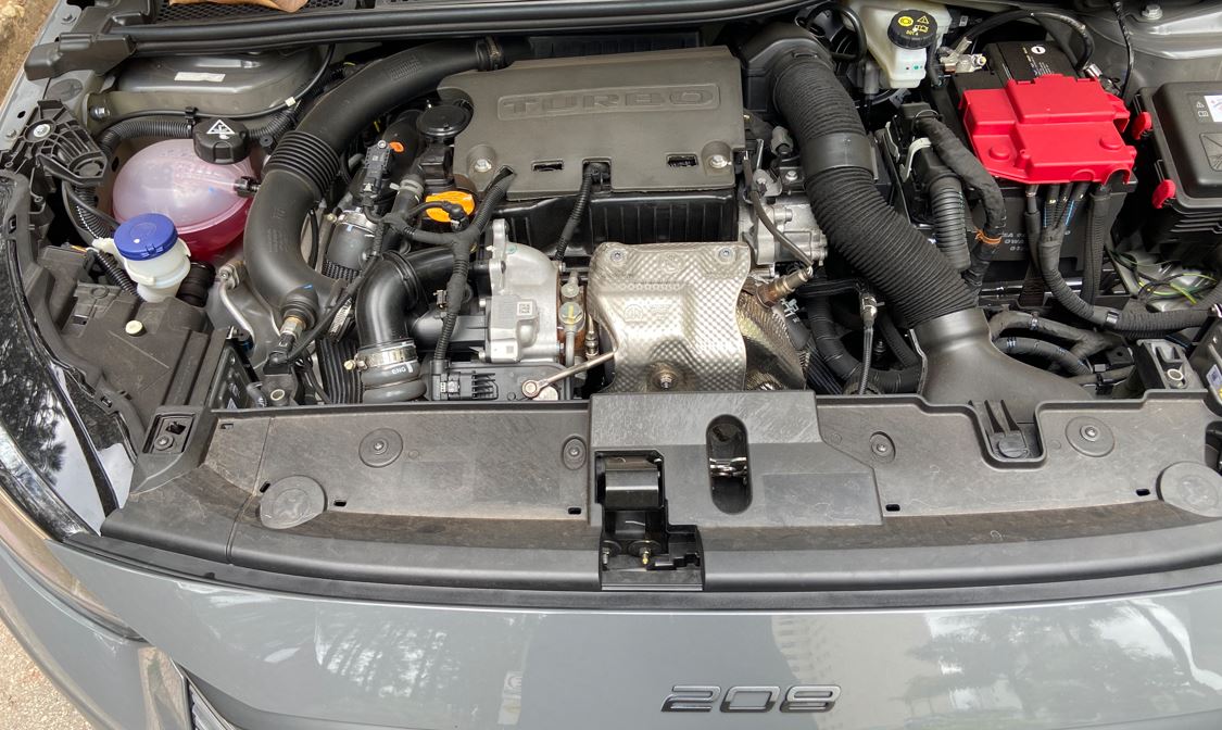 Motor Turbo 200 flex de 130 cv do Peugeot 208 GT híbrido com sistema MHEV 12V e componentes elétricos visíveis no cofre do motor.
