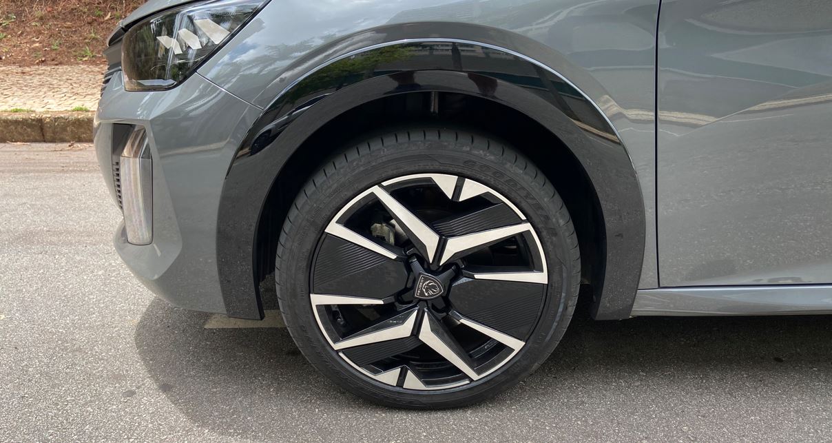 Detalhe da roda dianteira do Peugeot 208 GT híbrido, com aro 17”, acabamento diamantado e design esportivo em preto e prata.