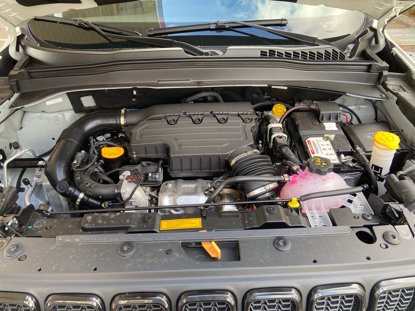 Motor T270 turbo flex do Jeep Renegade Willys 10 Anos, com 176 cavalos, sistema de admissão, bateria e reservatórios acessíveis visíveis.