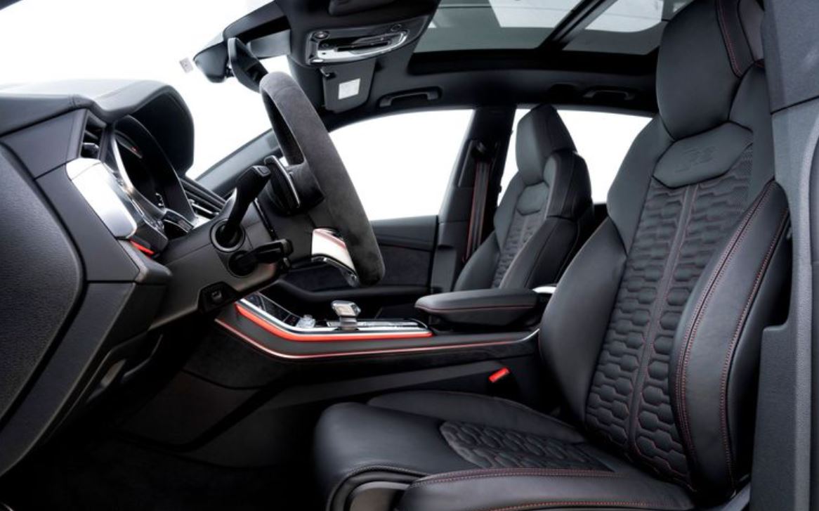 Interior do Audi RS Q8 Performance com volante esportivo em Alcantara, bancos em couro e iluminação personalizada em vermelho.