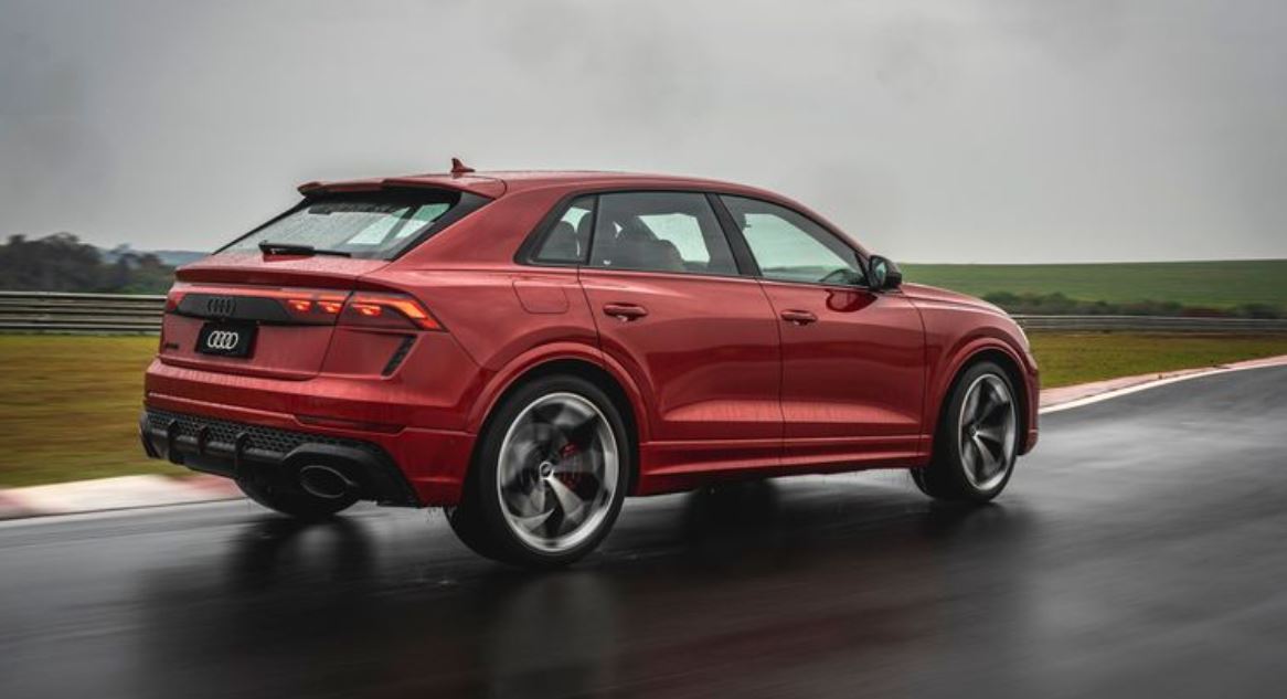 Audi RS Q8 Performance visto de traseira em pista molhada, exibindo design esportivo com lanternas OLED e difusor agressivo.