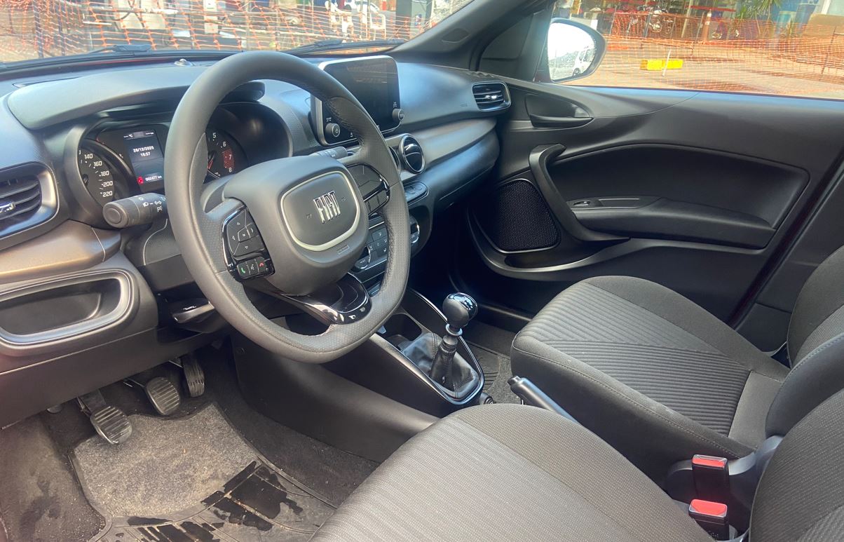 Interior do Fiat Cronos Drive 1.3 2026, com volante multifuncional, painel escurecido, central multimídia e câmbio manual.