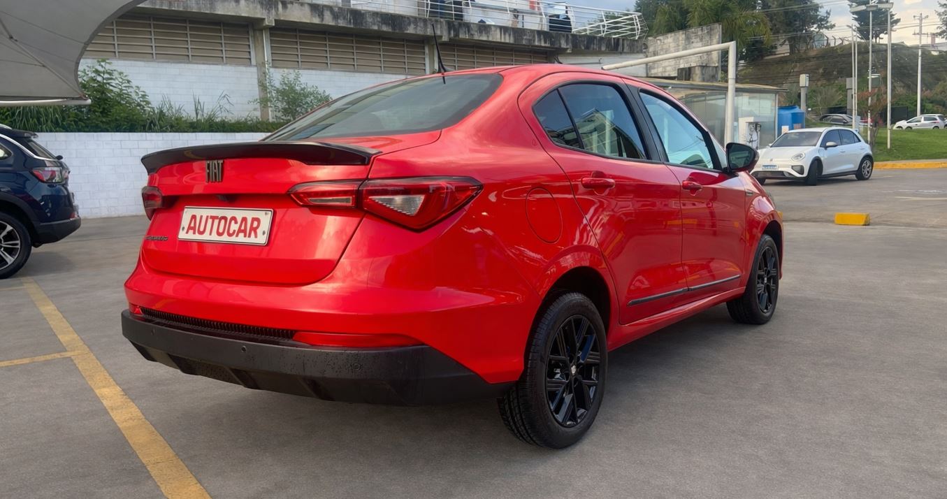 Vista traseira lateral do Fiat Cronos Drive 1.3 2026 em acabamento vermelho, destacando rodas pretas e aerofólio integrado.