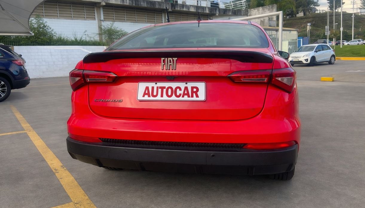 Vista traseira do Fiat Cronos Drive 1.3 2026 com lanternas redesenhadas, aerofólio preto e placa personalizada AUTOCAR.