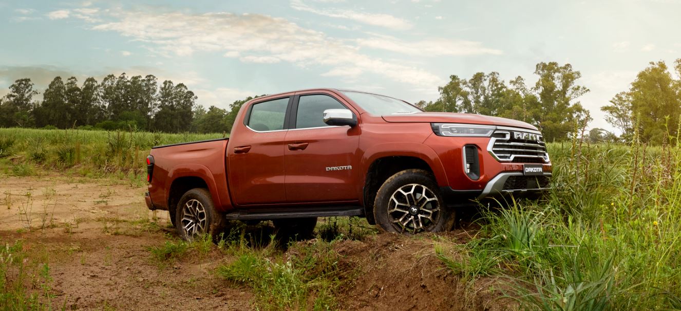 Ram Dakota Laramie 2026 em terreno irregular, exibindo perfil lateral, rodas exclusivas, suspensão elevada e visual robusto em ambiente off-road.