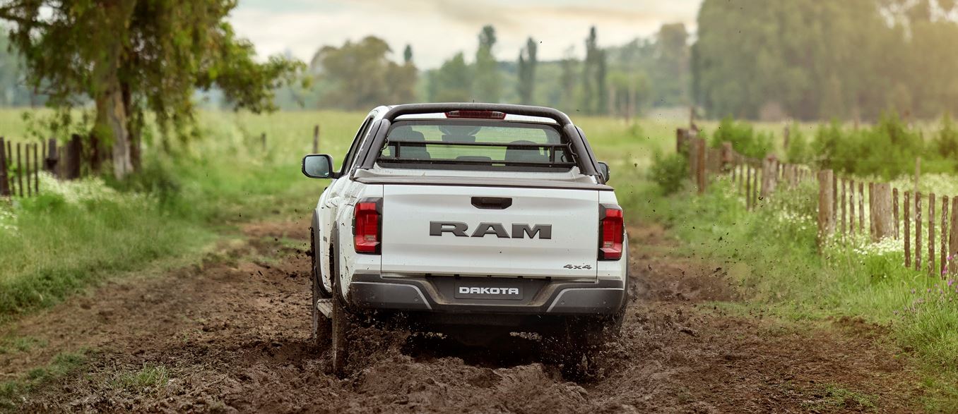 Traseira da Ram Dakota Laramie 2026 com caçamba funcional, lanternas verticais em LED, logotipo RAM em destaque e indicação de tração 4x4.