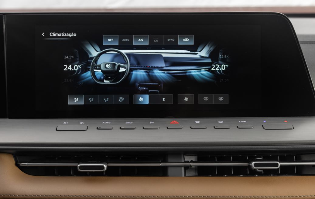 Central multimídia da Ram Dakota Laramie 2026 com tela ampla, interface digital do ar-condicionado dual zone e comandos físicos integrados.
